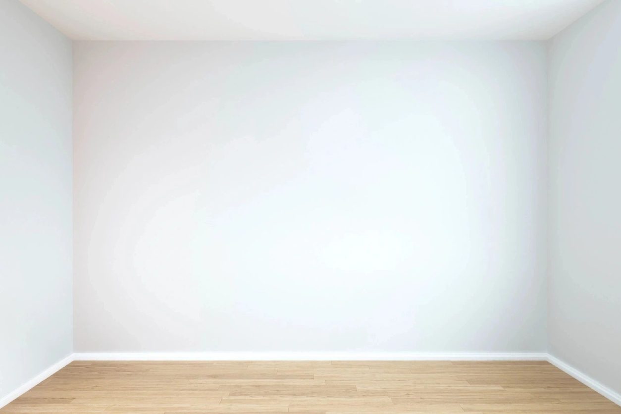 A white wall with wood floors in front of it.