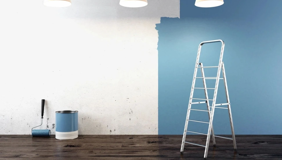 A ladder in front of a wall with blue paint.